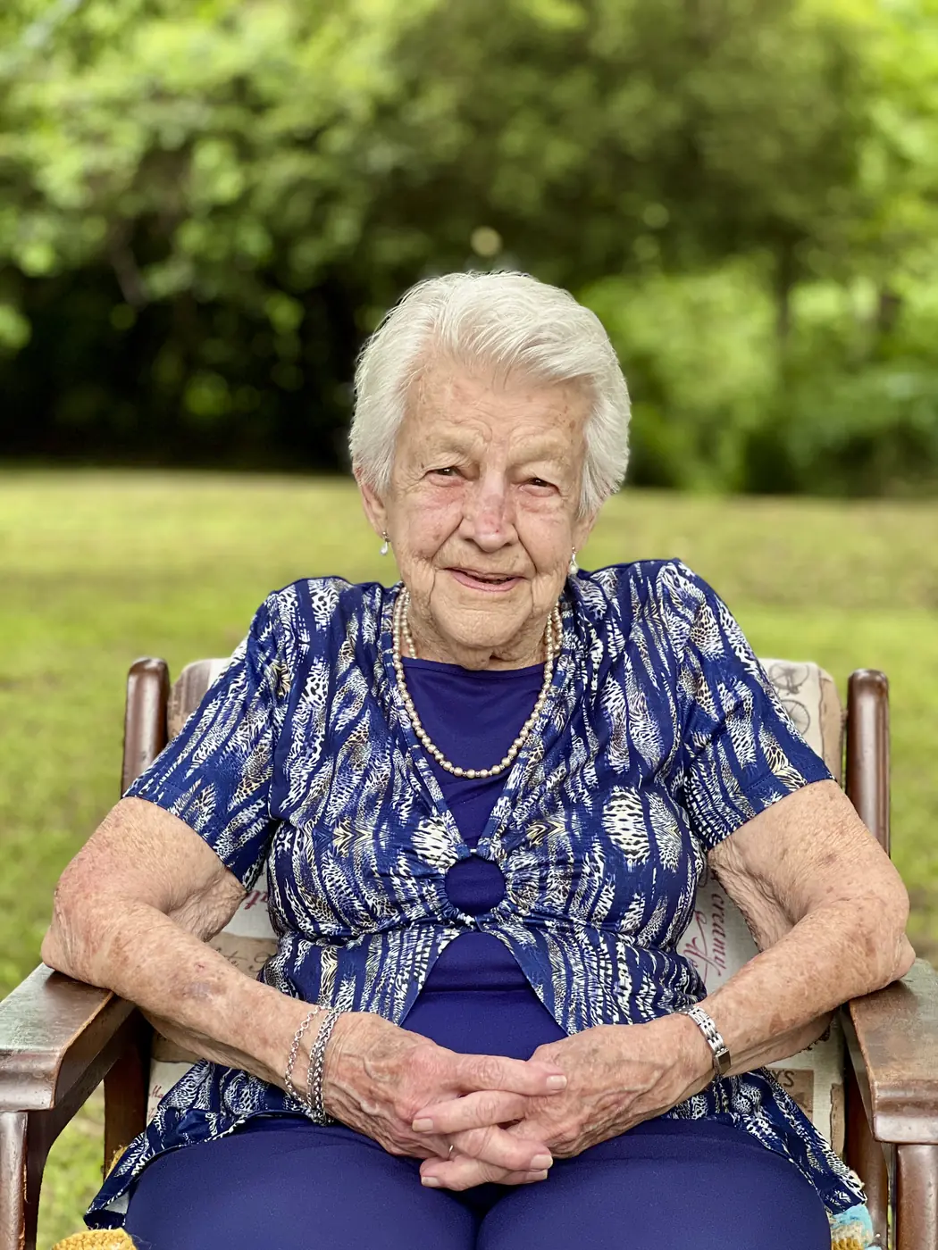 Doreen, a 92-year-old woman, smiling warmly in her armchair outdoors, living an independent life and able to get in and out of her chair on her own