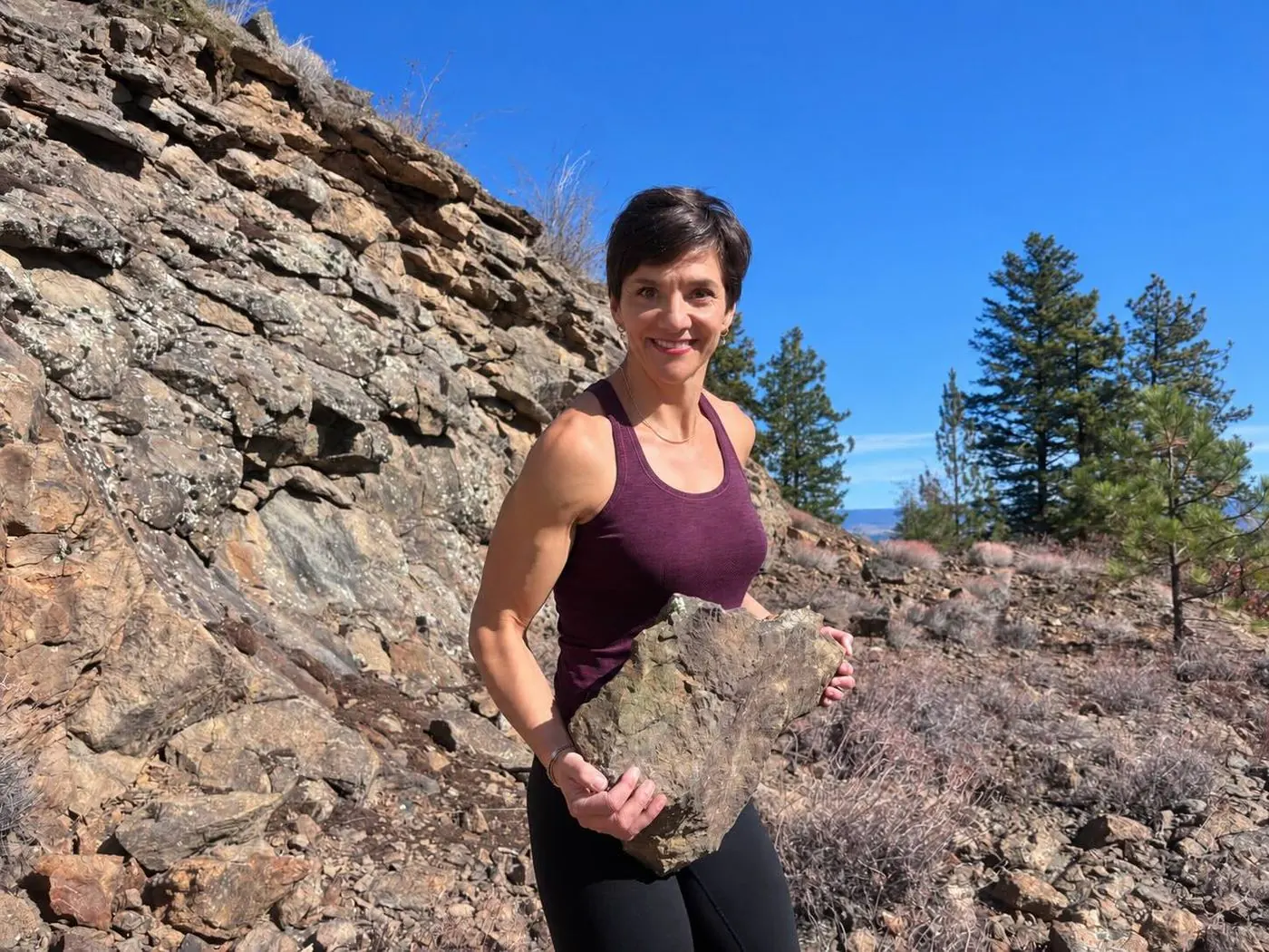 Yvette carrying a large rock outdoors, demonstrating real-world strength